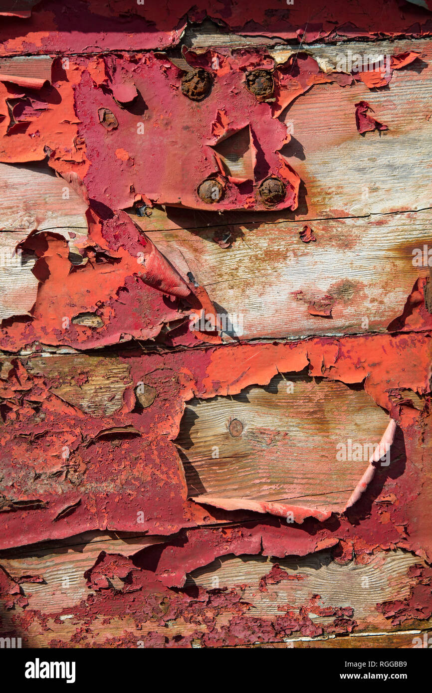 Detail of red paint peeling off an old wooden fishing boat, Ireland. Stock Photo