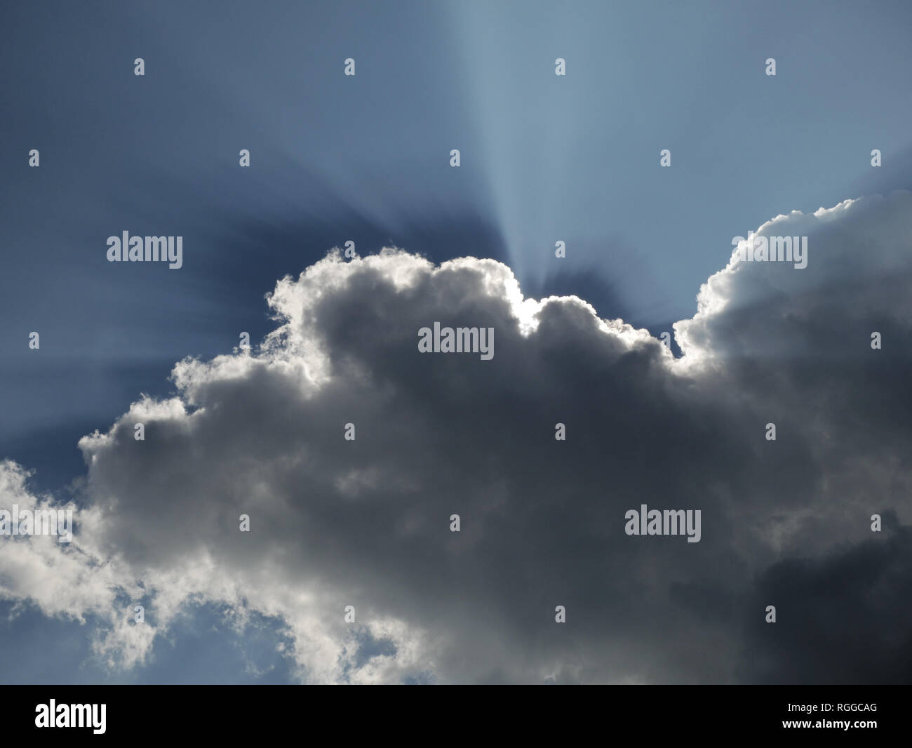 sun rays behind clouds in the sky Stock Photo