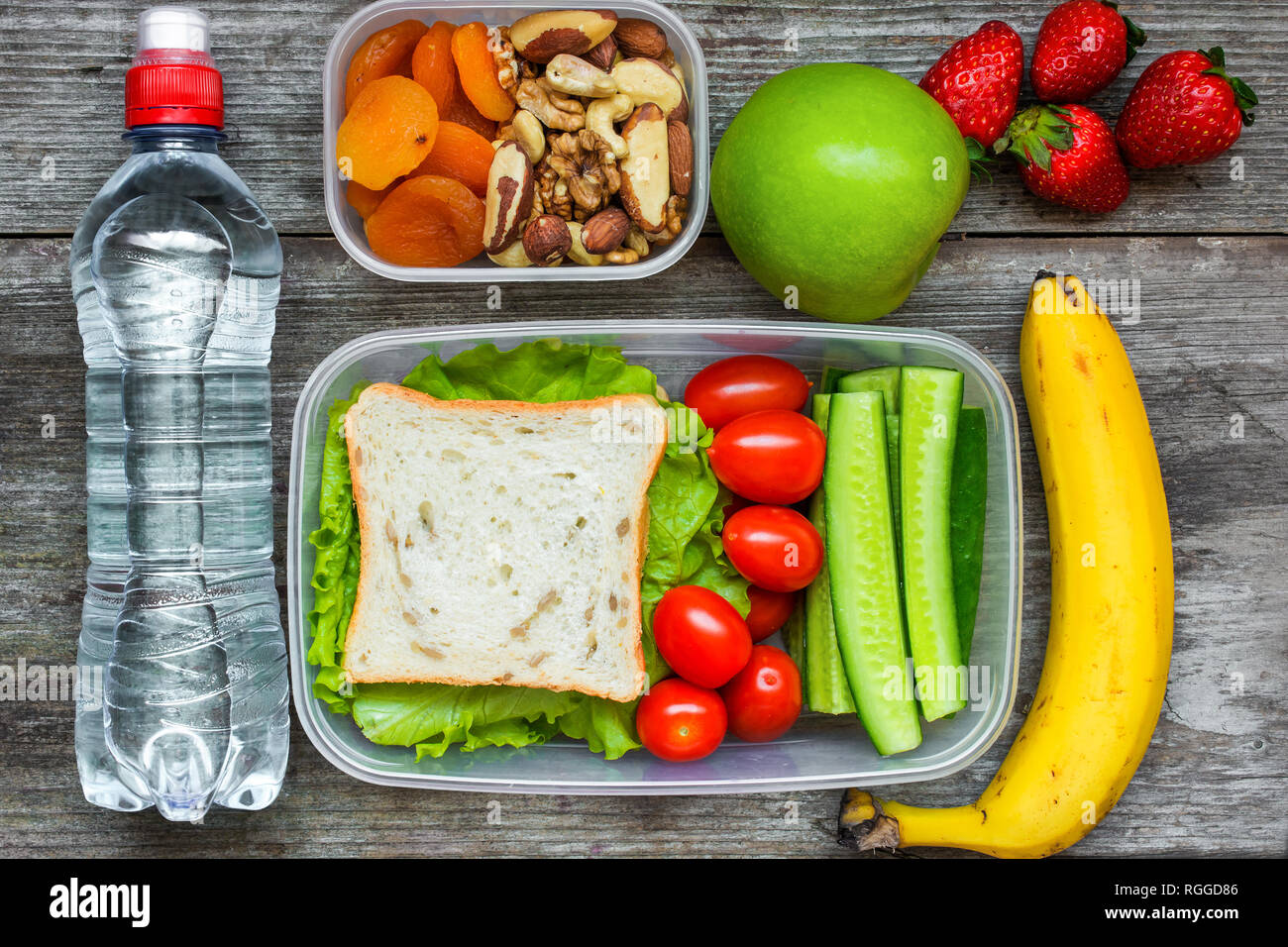 https://c8.alamy.com/comp/RGGD86/healthy-lunch-boxes-with-sandwich-and-fresh-vegetables-bottle-of-water-nuts-and-fruits-on-rustic-wooden-background-top-view-RGGD86.jpg