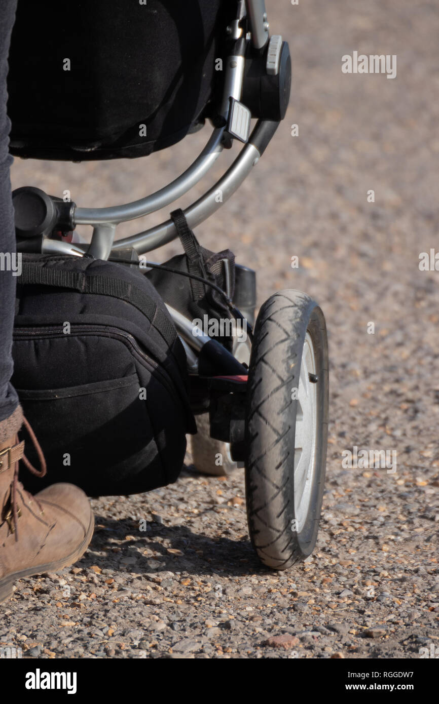 the wheel of a pram being pushed by a mother Stock Photo