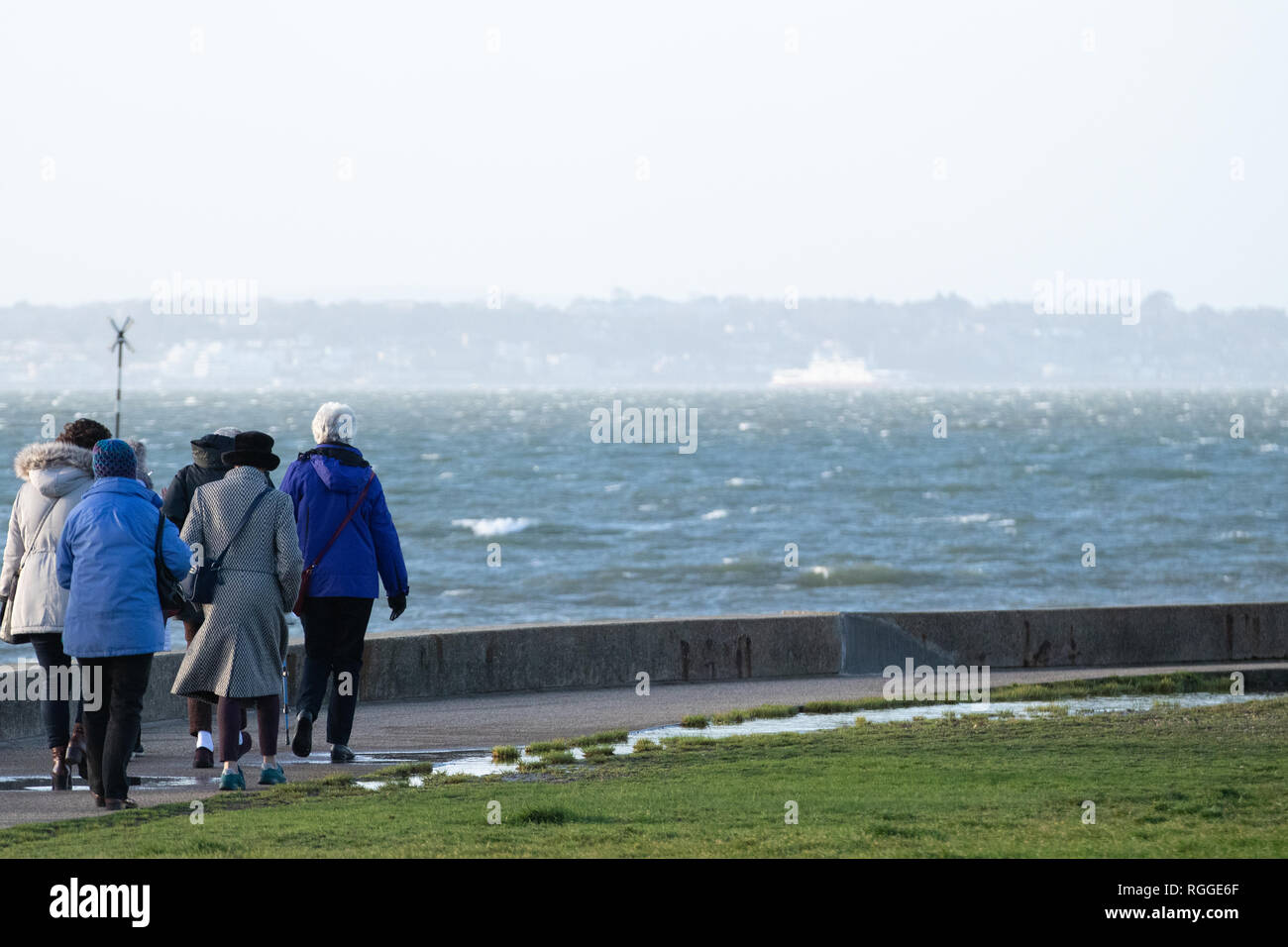 A group of elderly people taking a seaside walk on a very windy day Stock Photo