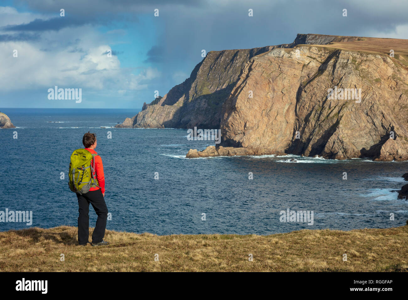Coastal walker admiring the 260m sea cliffs of Benwee Head from the Children of Lir Loop Walk. Carrowteige, County Mayo, Ireland. Stock Photo
