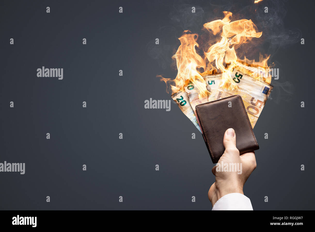 Burning Euro bills in a hand-held wallet Stock Photo