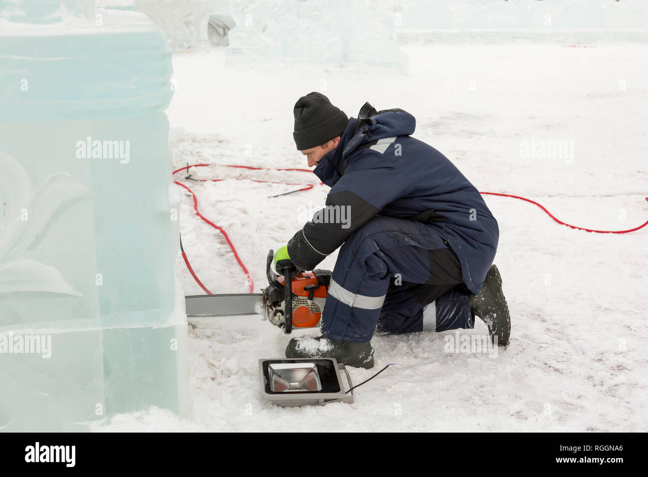 The installer cuts a niche with a chainsaw under the LED lamp to illuminate  the ice figure Stock Photo - Alamy