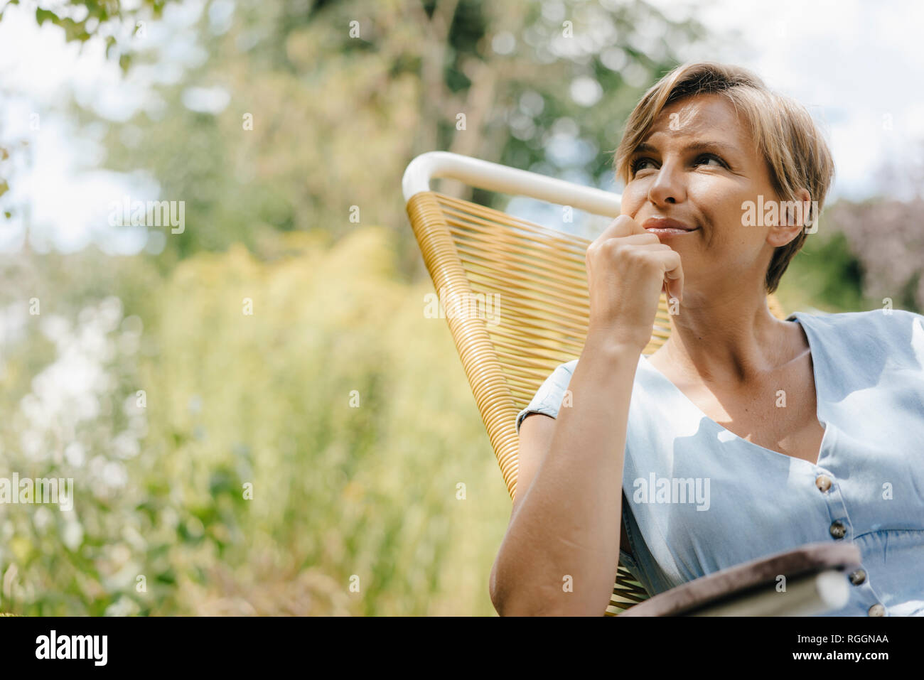 Portrait of woman sitting in garden on chair Stock Photo - Alamy