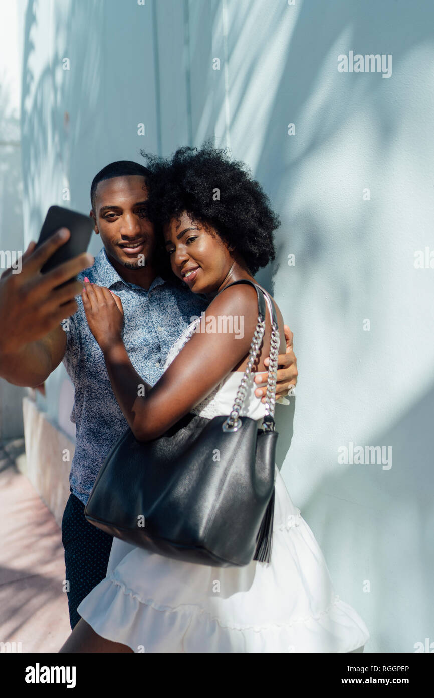 Smiling young couple embracing and taking a selfie Stock Photo