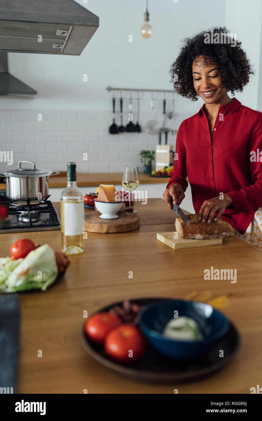 Woman standing in kitchen, slicing bread Stock Photo