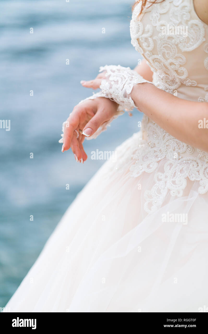 bride on the background of the sea in a white wedding dress and gloves ...