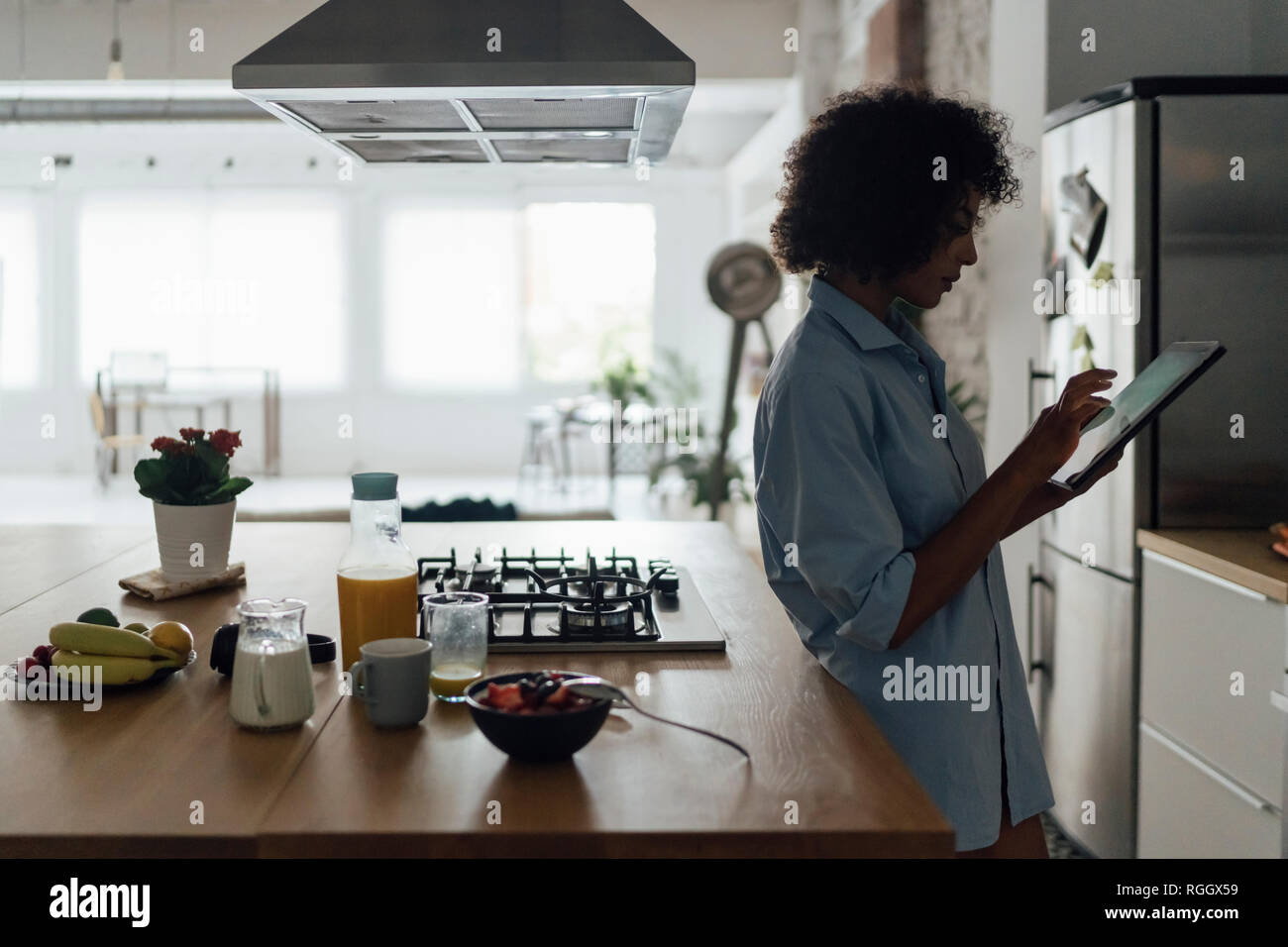 Woman standing in her kitchen, using digital tablet Stock Photo