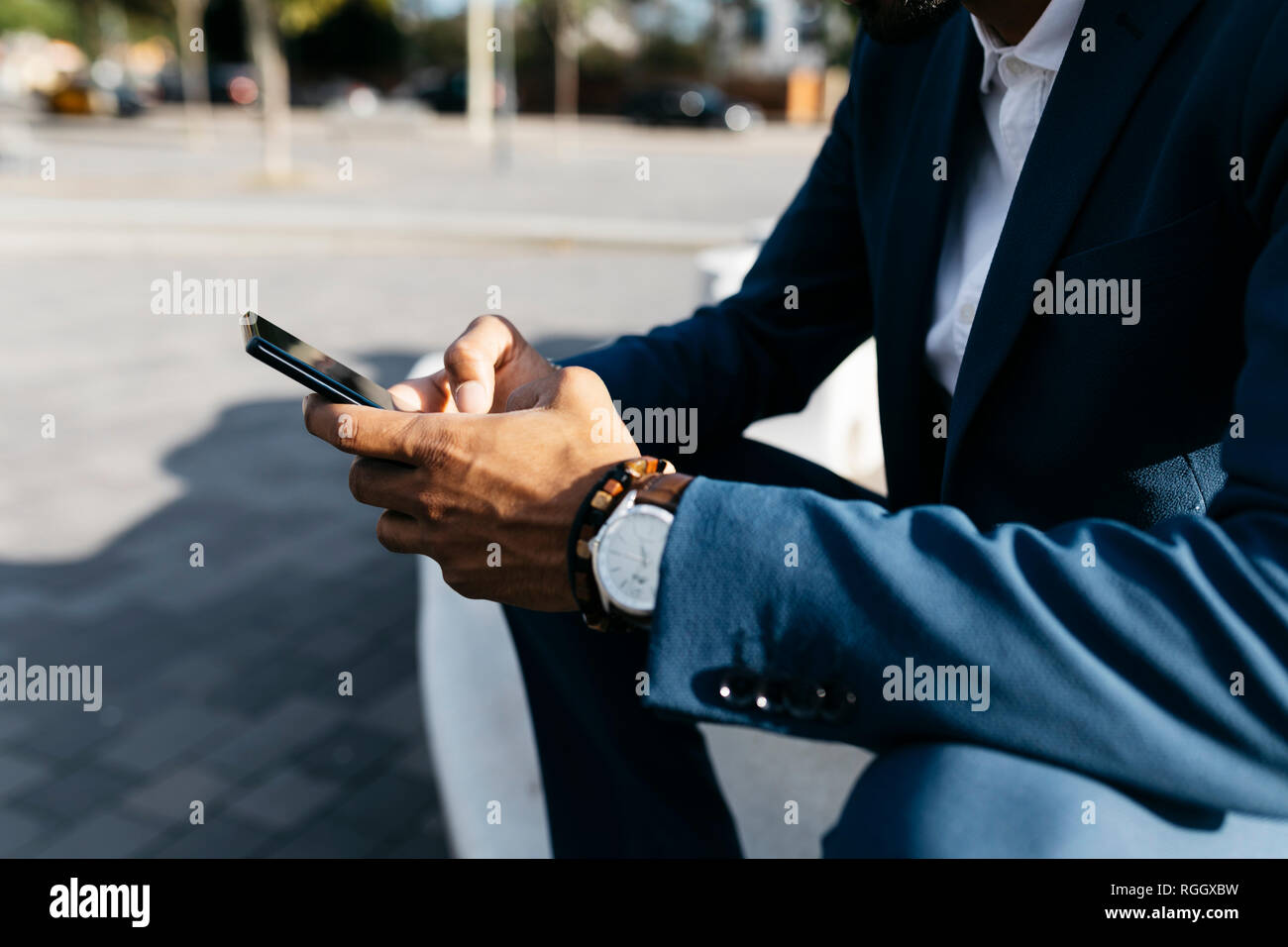 Close-upof businessman sitting outdoors using cell phone Stock Photo