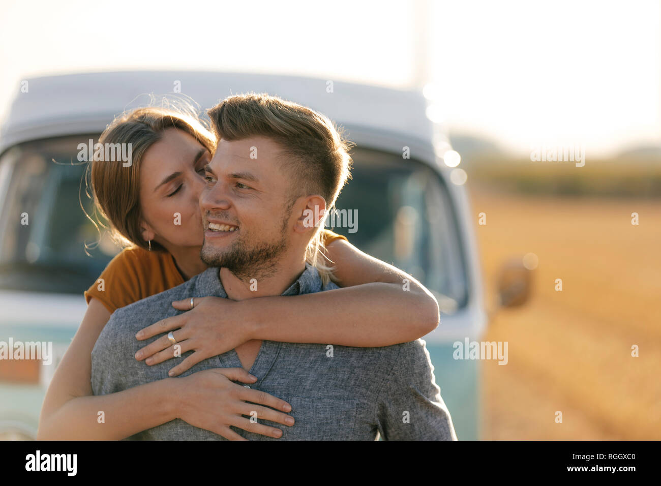 Happy affectionate young couple at camper van in rural landscape Stock Photo