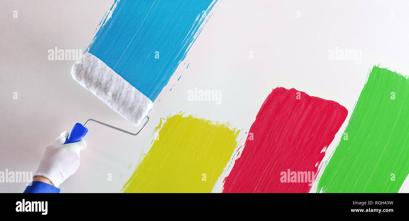 Professional painter's hand painting multicolored samples with roller on a white wall. Horizontal composition. Stock Photo