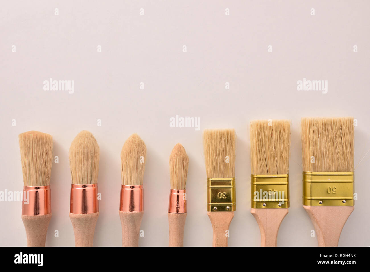 Set of paintbrushes for house painter of various sizes and shapes aligned on white table. Horizontal composition Stock Photo