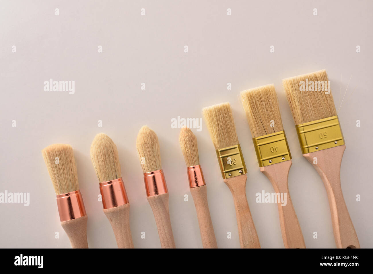 Set of paintbrushes for house painter of various sizes and shapes aligned diagonal on white table. Horizontal composition Stock Photo