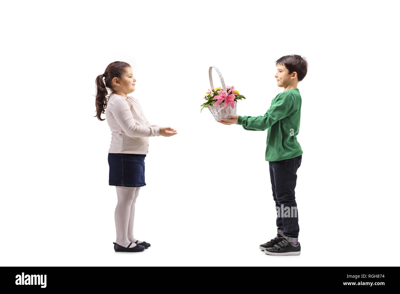 Full length shot of a little boy giving a basket with flowers to a little girl isolated on white background Stock Photo