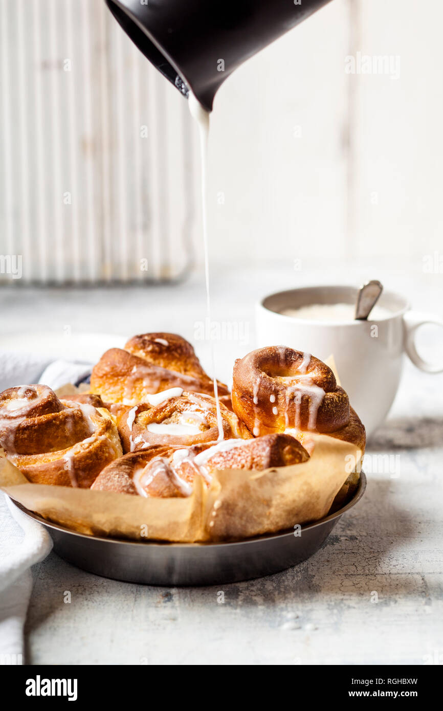 Garnishing home-baked cinnamon buns with icing sugar Stock Photo
