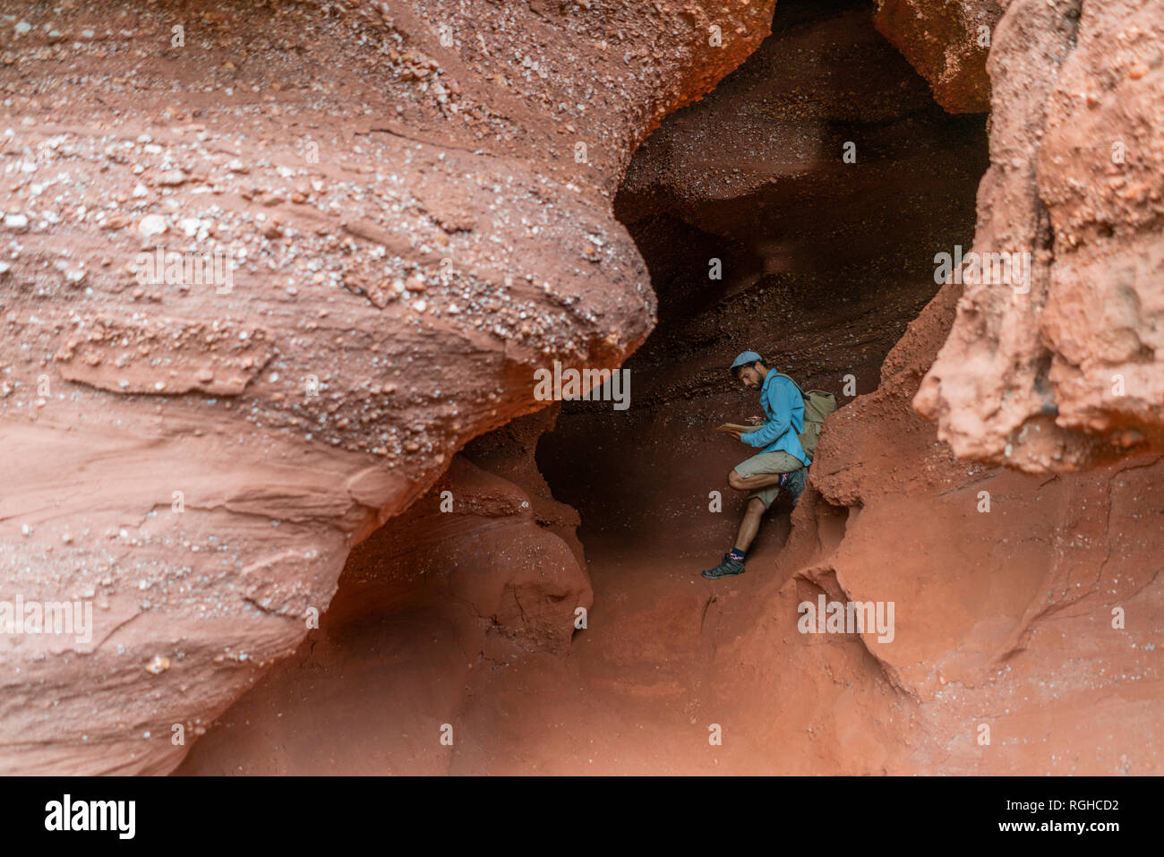 Young man sitting in a cave, looking at map Stock Photo