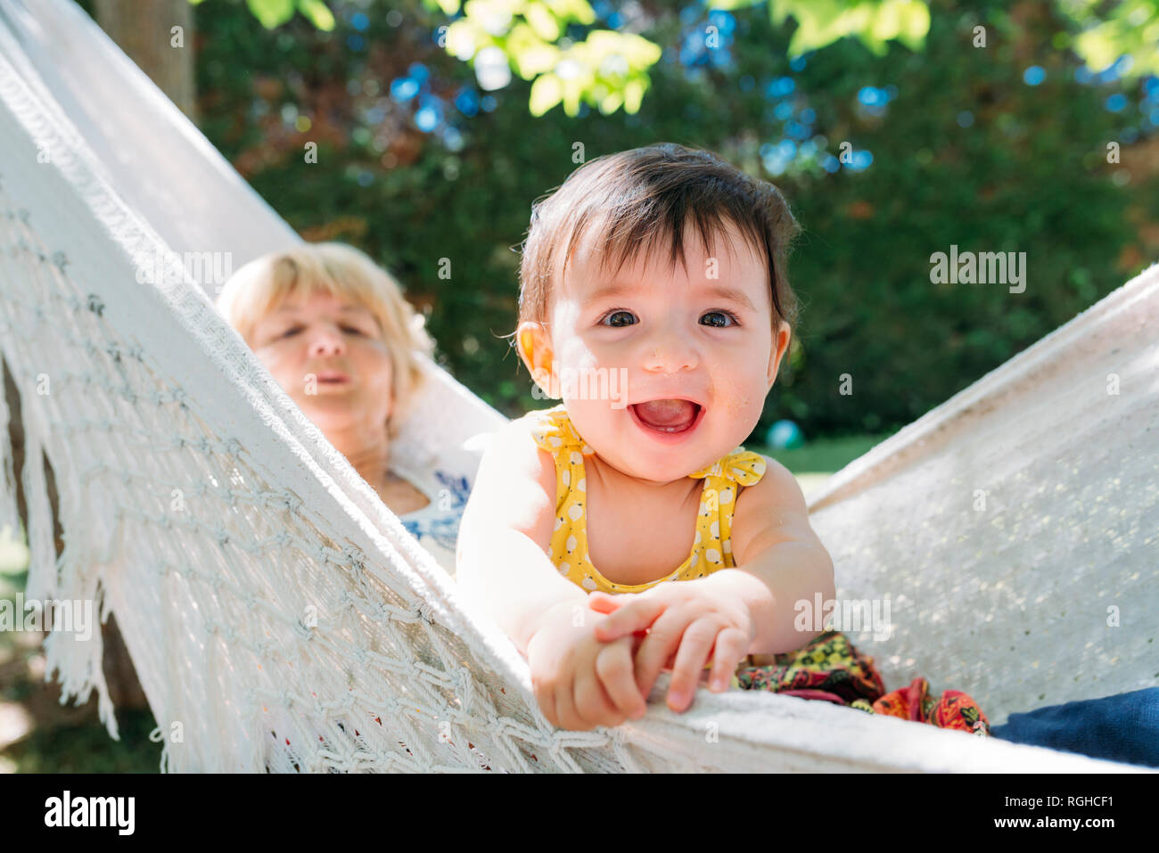 Spain, Grandma and baby relaxing in a hammock in the garden in the summer Stock Photo