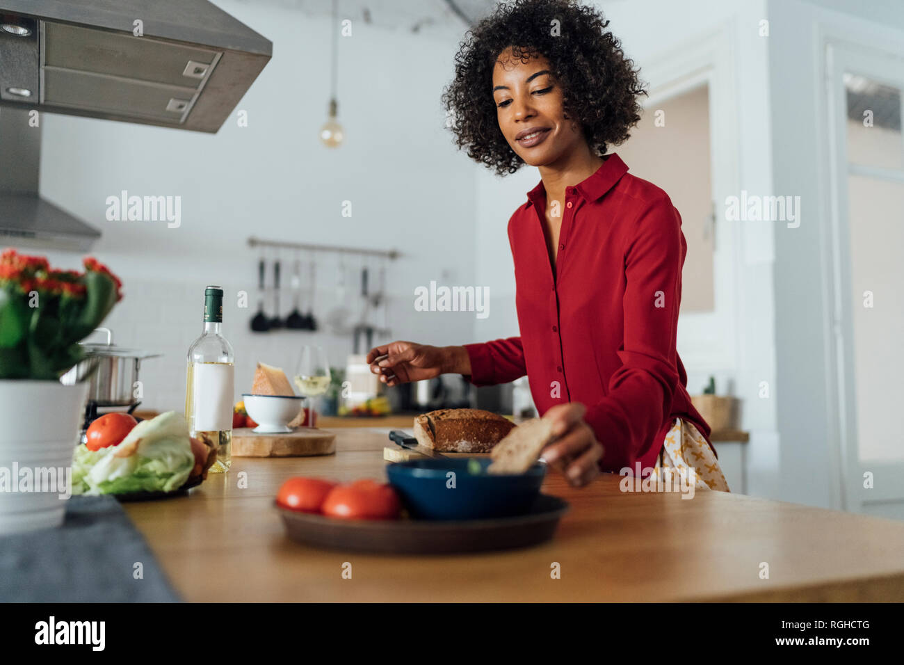 Woman standing in kitchen, slicing bread Stock Photo