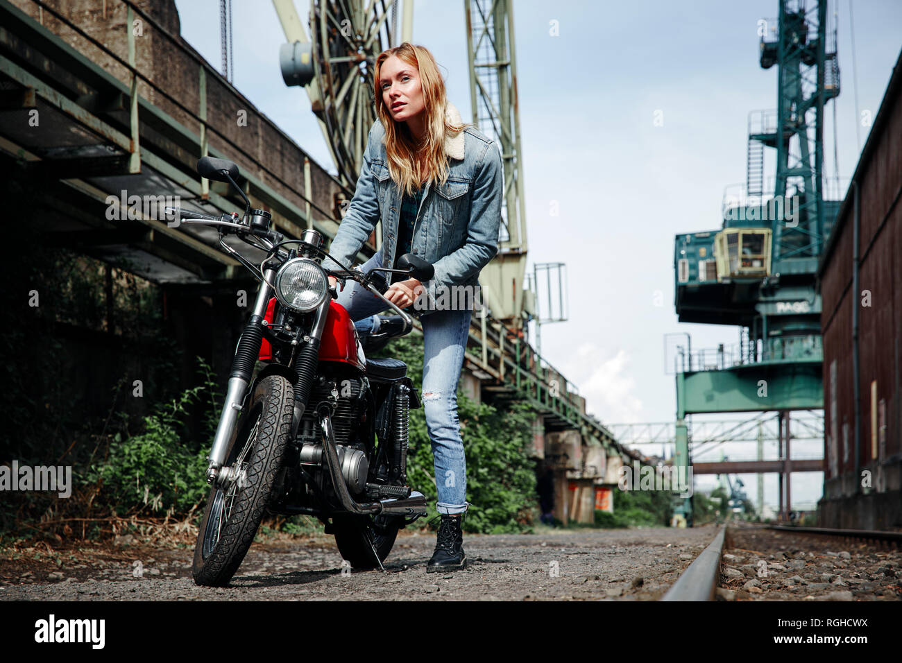 Portrait of confident young woman getting on motorcycle Stock Photo