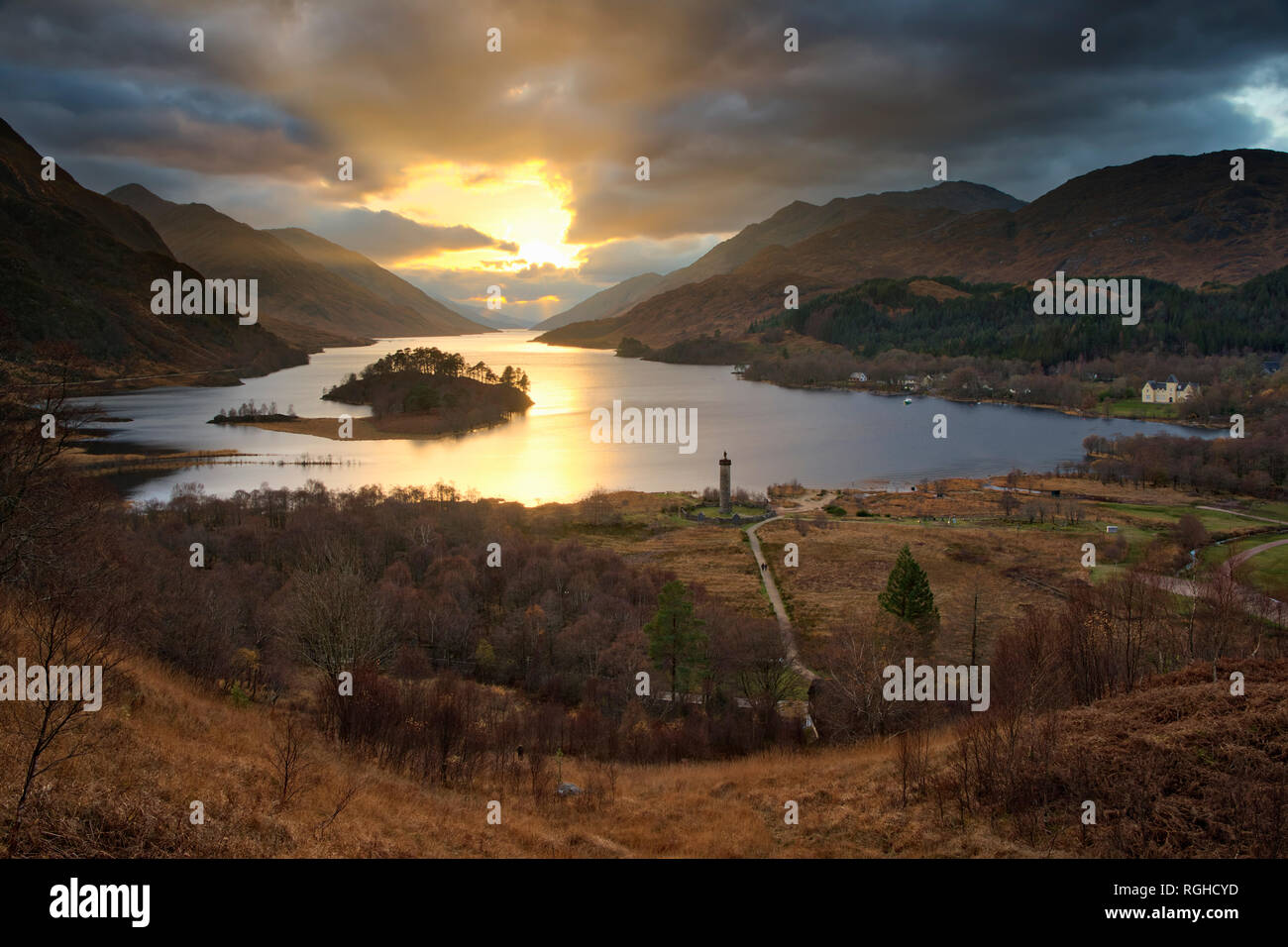 The setting sun over Loch Sheil with the Glenfinnan monument in the foreground. Stock Photo