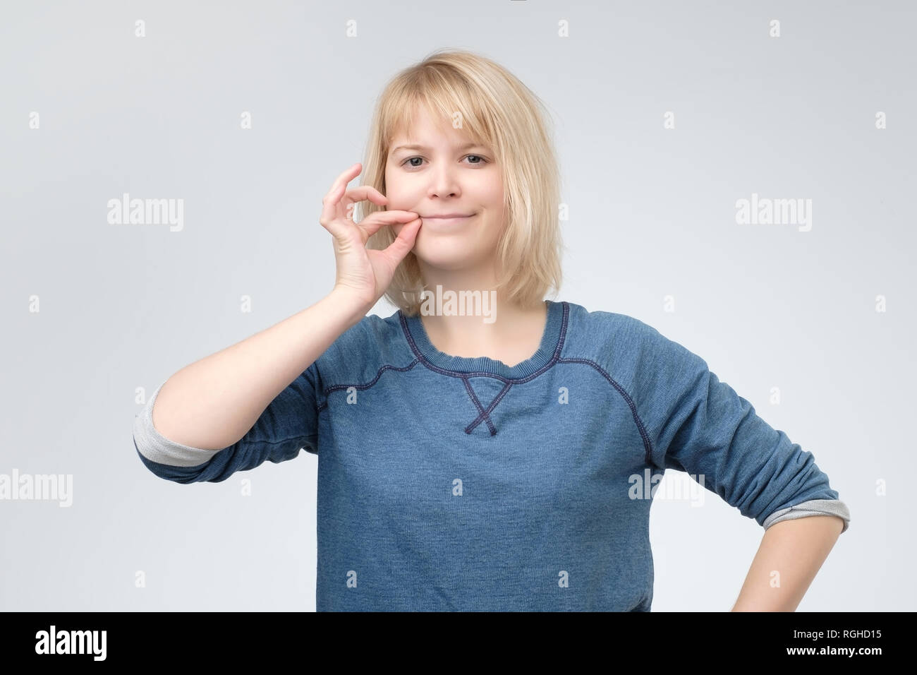 Keep a secret, woman zipping her mouth shut. Stock Photo