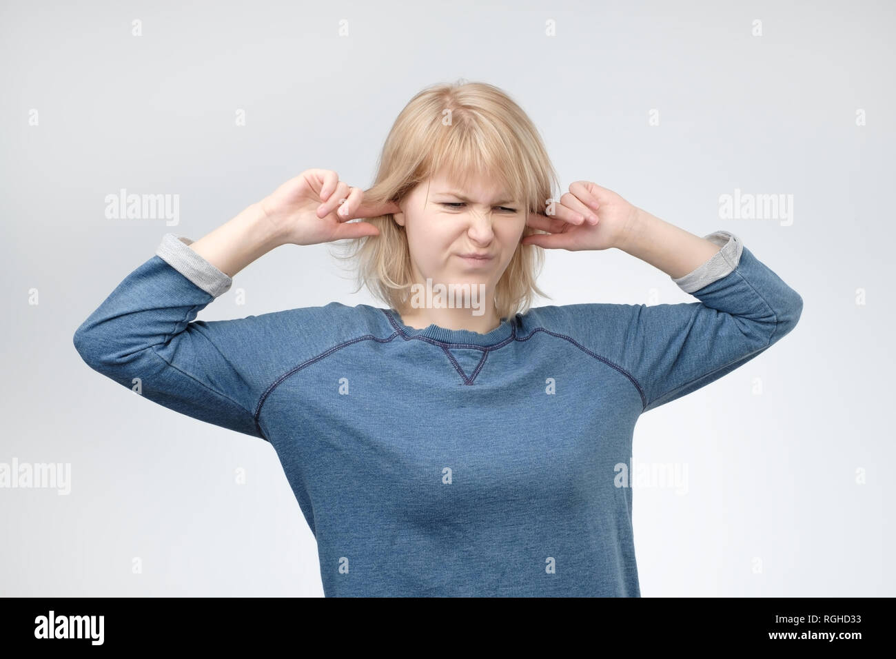 Young european woman plugging ears, looking up, pretending not to hear what she is told Stock Photo