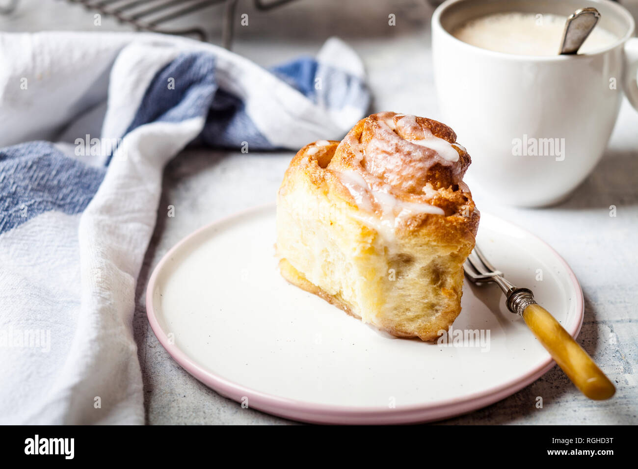 Home-baked cinnamon bun with icing sugar and a cup of coffee Stock Photo