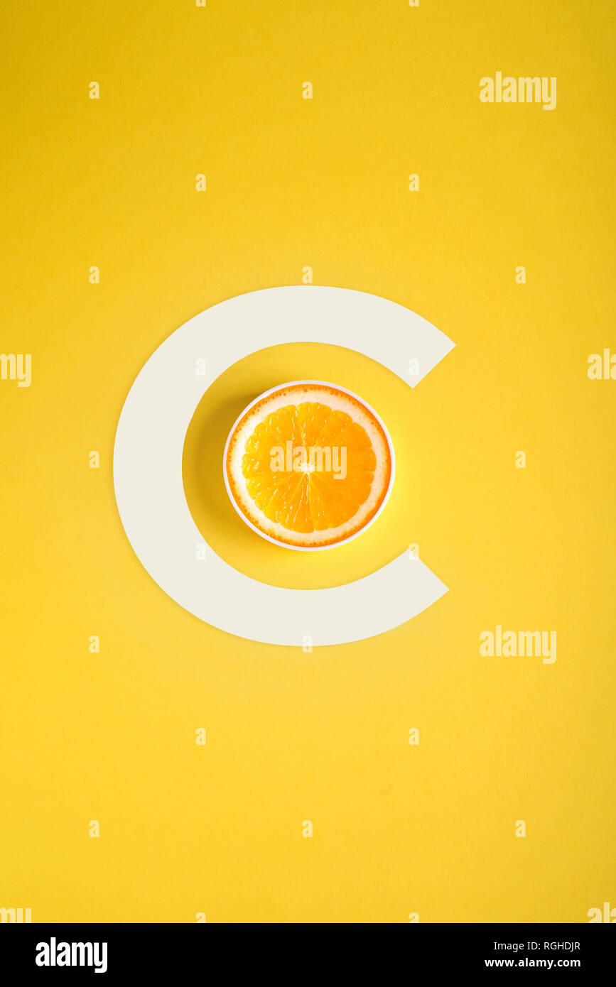 Concept of Vitamin C, orange and letter C on a yellow background Stock