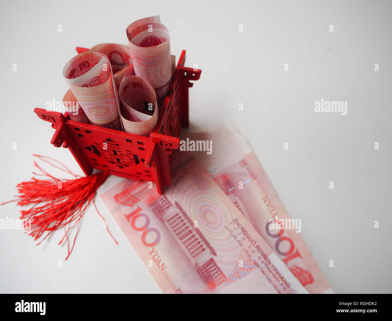 Miniature Chinese pavilion in bright red standing on and filled with Chinese 100 renminbi banknotes Stock Photo