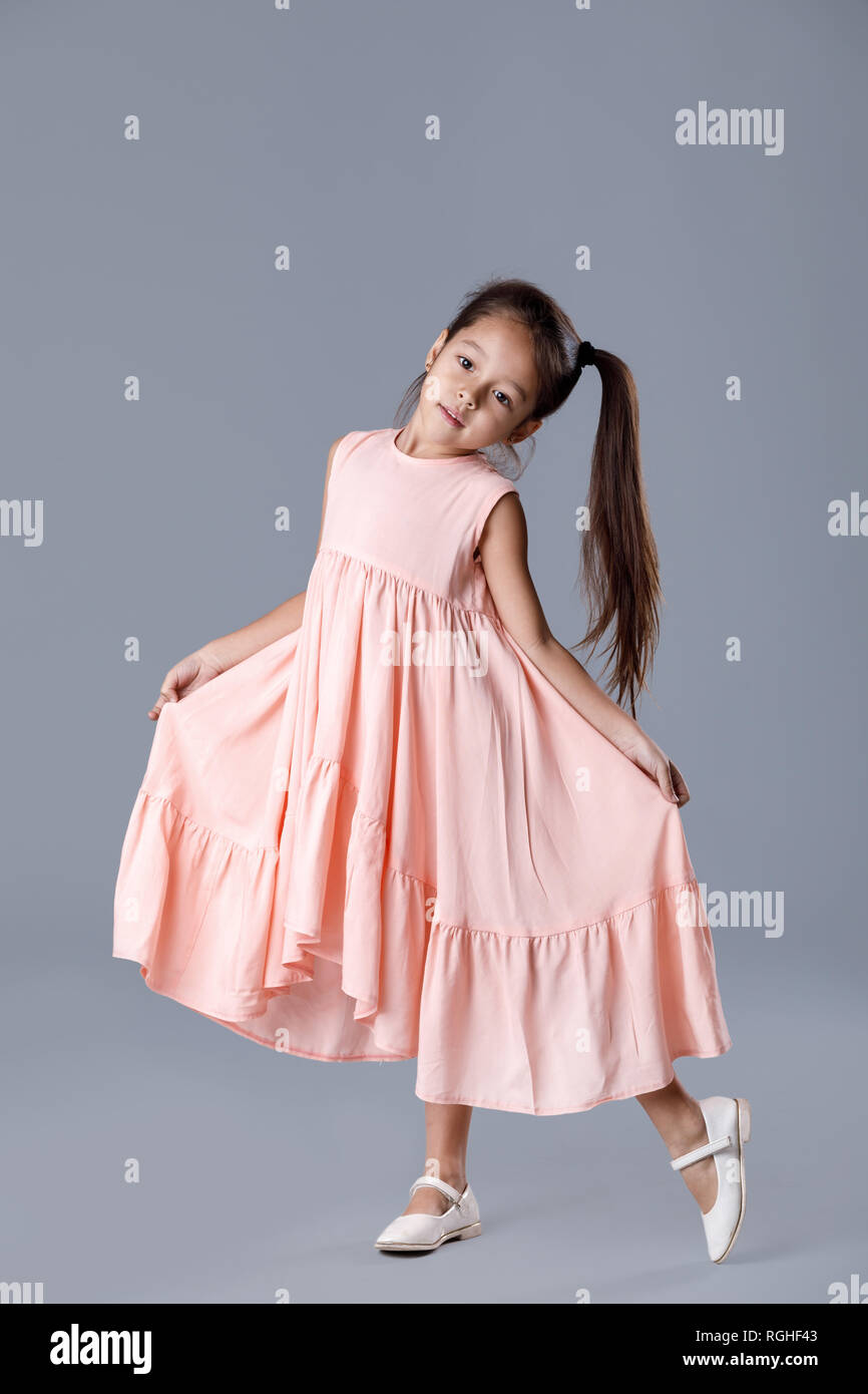 little girl in pink dress posing on gray background Stock Photo - Alamy