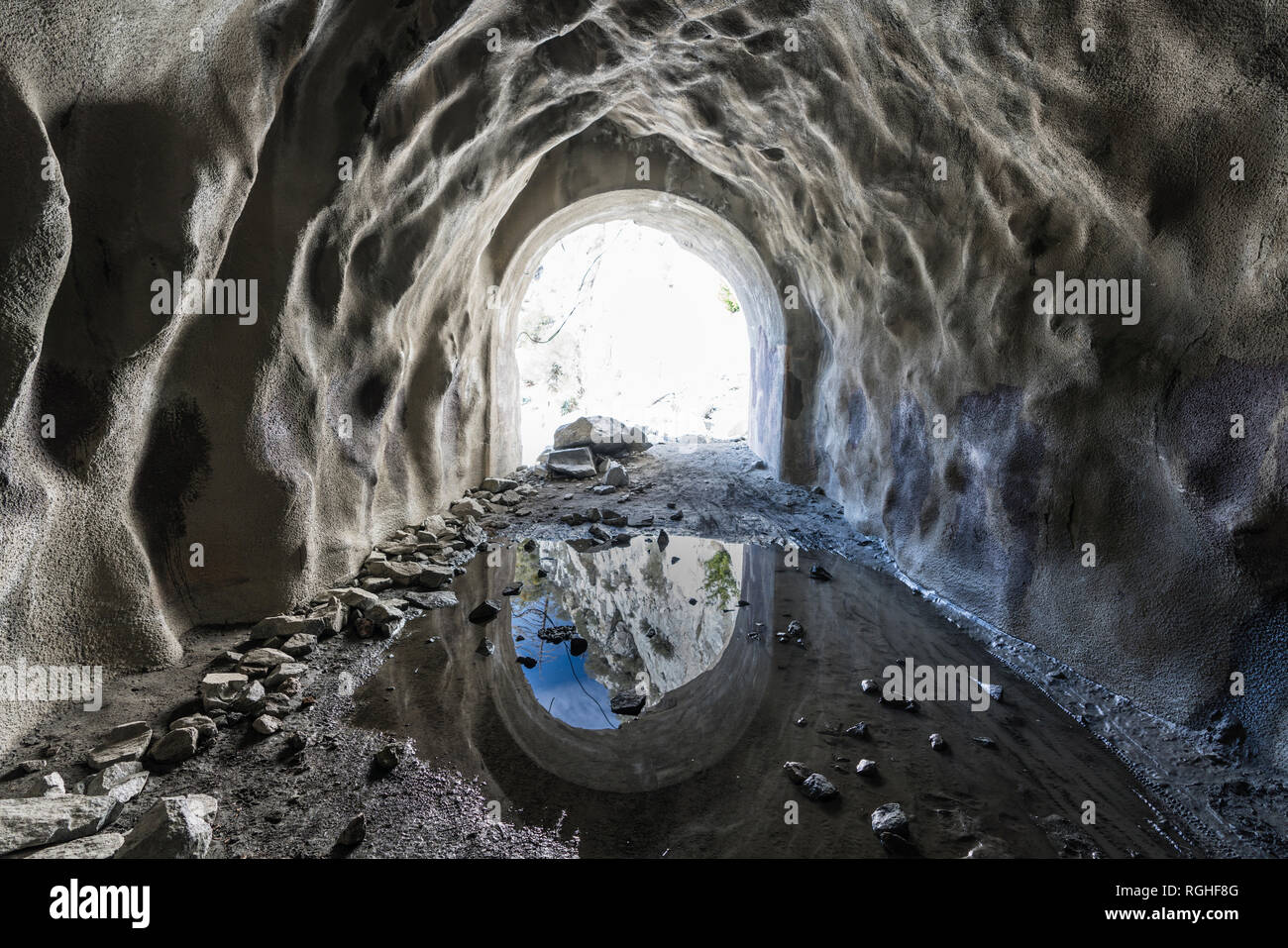 Inside wet, muddy, abandoned mountain mine entrance tunnel. Stock Photo