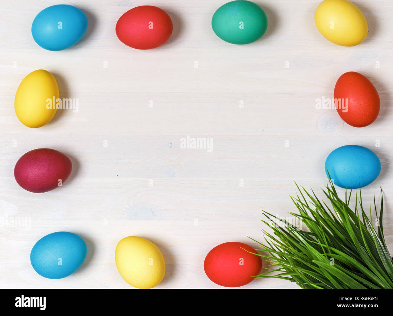 Multi-colored eggs and artificial green grass on a white background. Easter concept. Copy space Stock Photo
