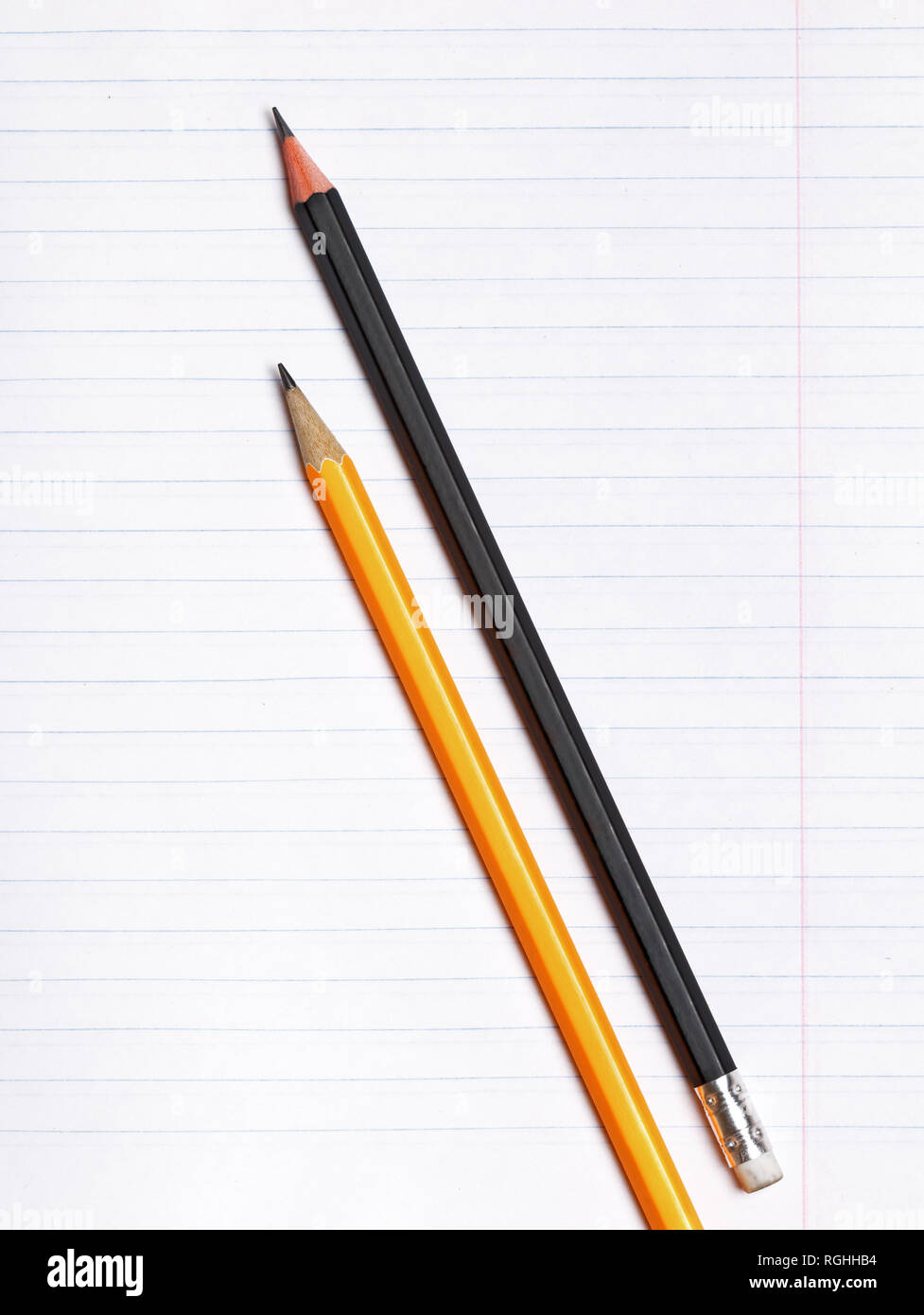 On a sheet of paper notebook with lines are black and yellow graphite pencils. Copy space. The concept of education. Flat surface Stock Photo