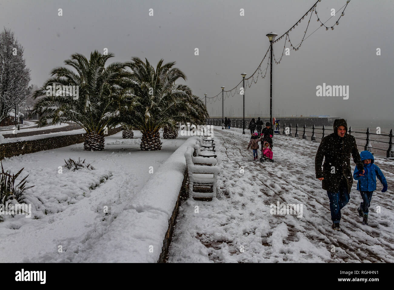 People struggle with the snow and icy conditions while walking along Torquay seafront during the 'Beast from the East' storm in March 2018. Stock Photo