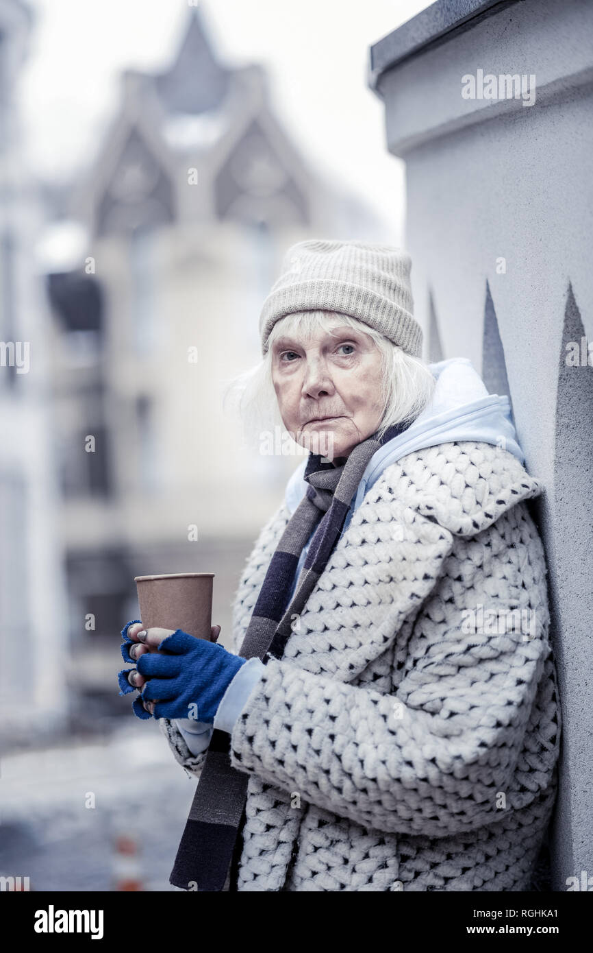 Depressed aged woman asking you for money Stock Photo