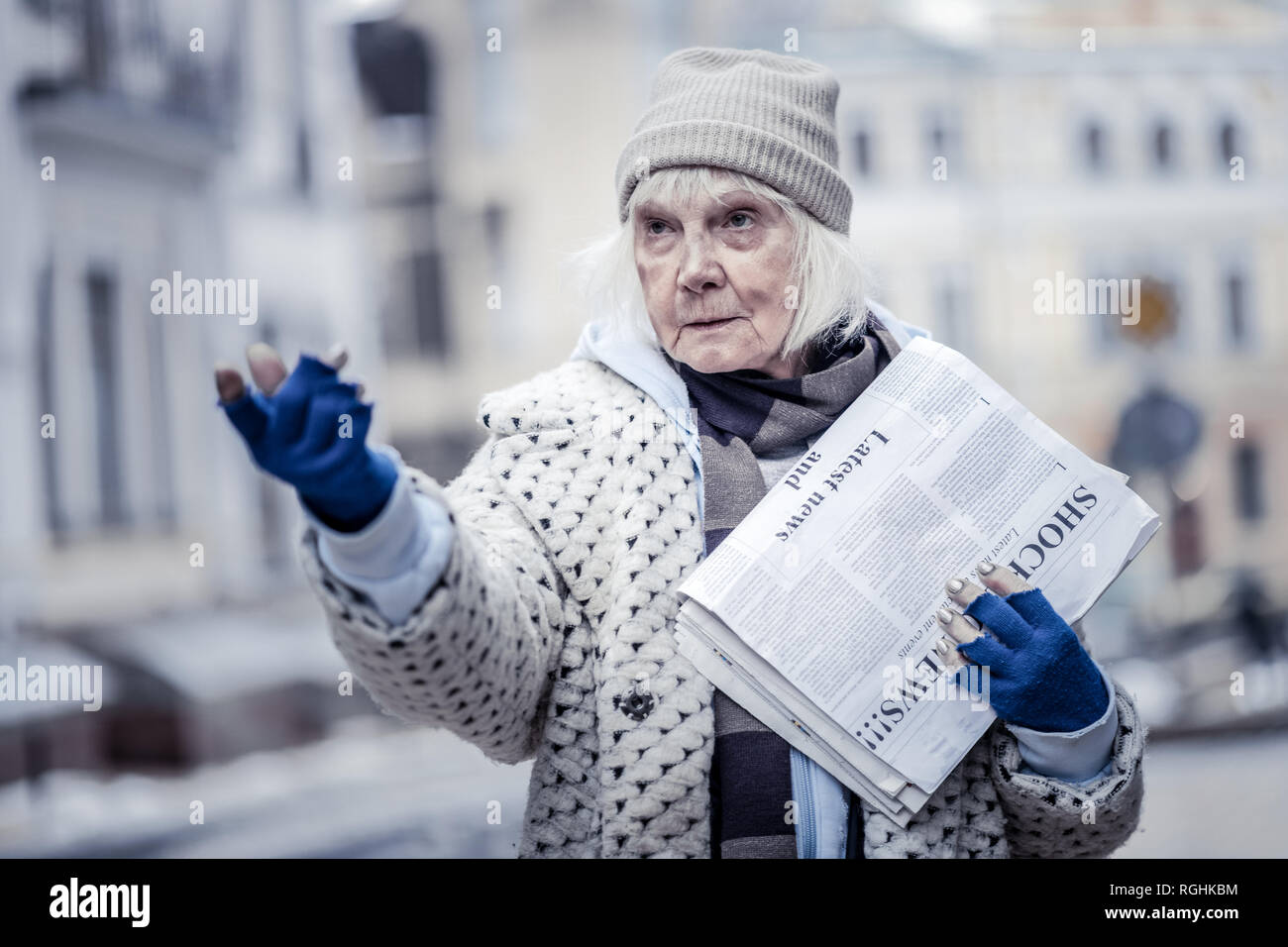 Unhappy aged woman selling newspapers to people Stock Photo