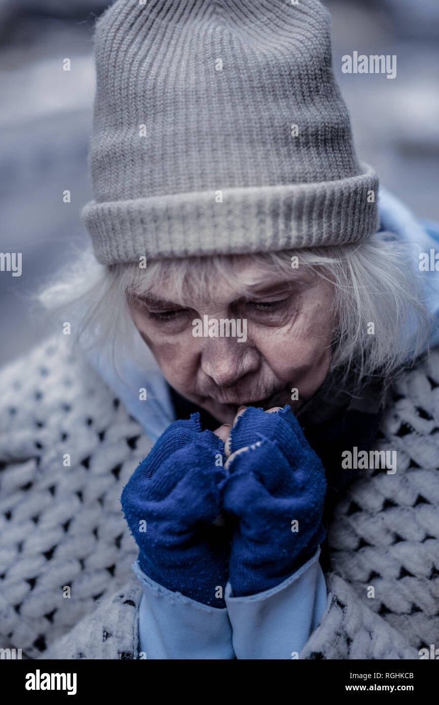 Depressed homeless woman trying to warm her hands Stock Photo