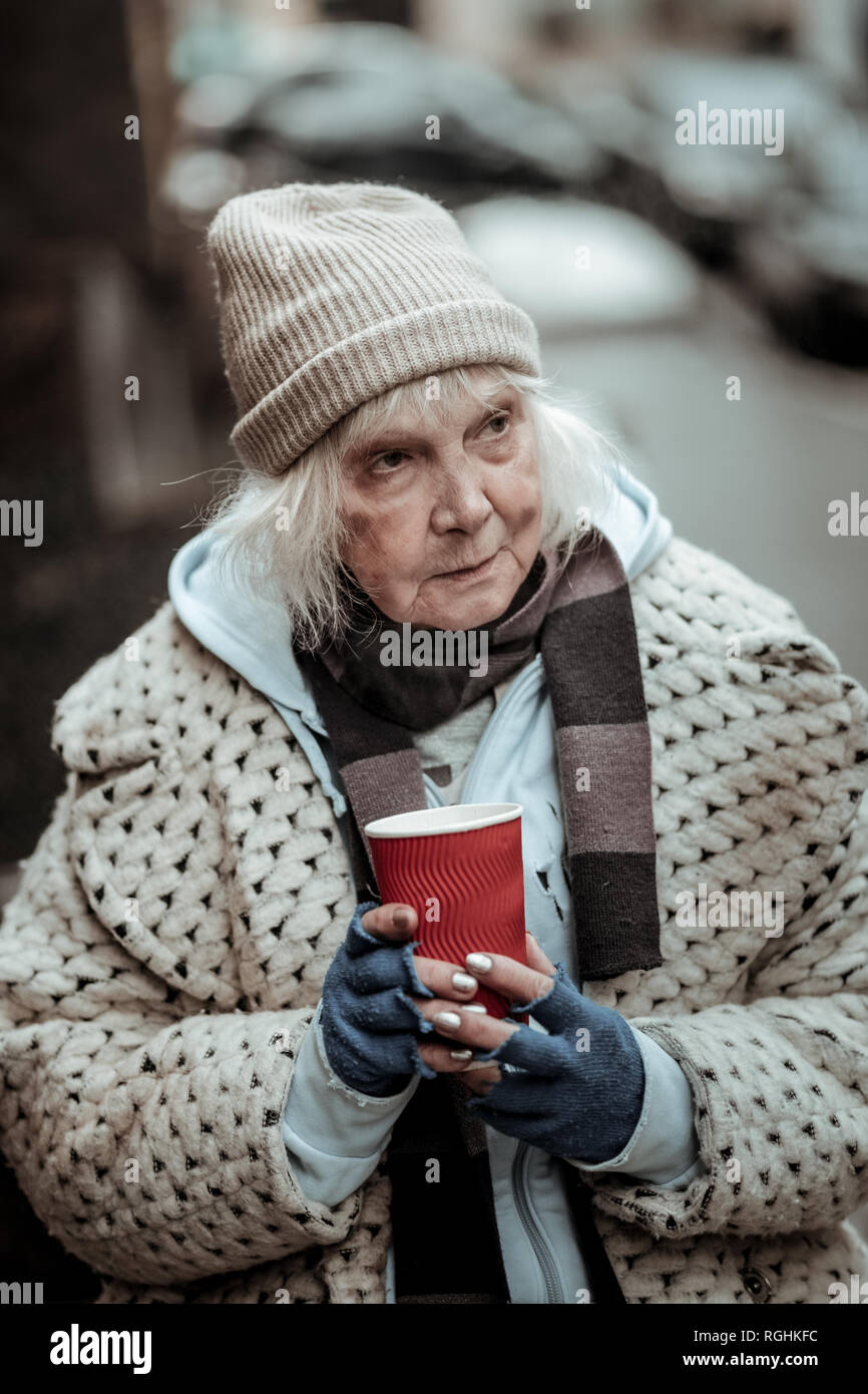 Depressed homeless woman standing with a cup of tea Stock Photo