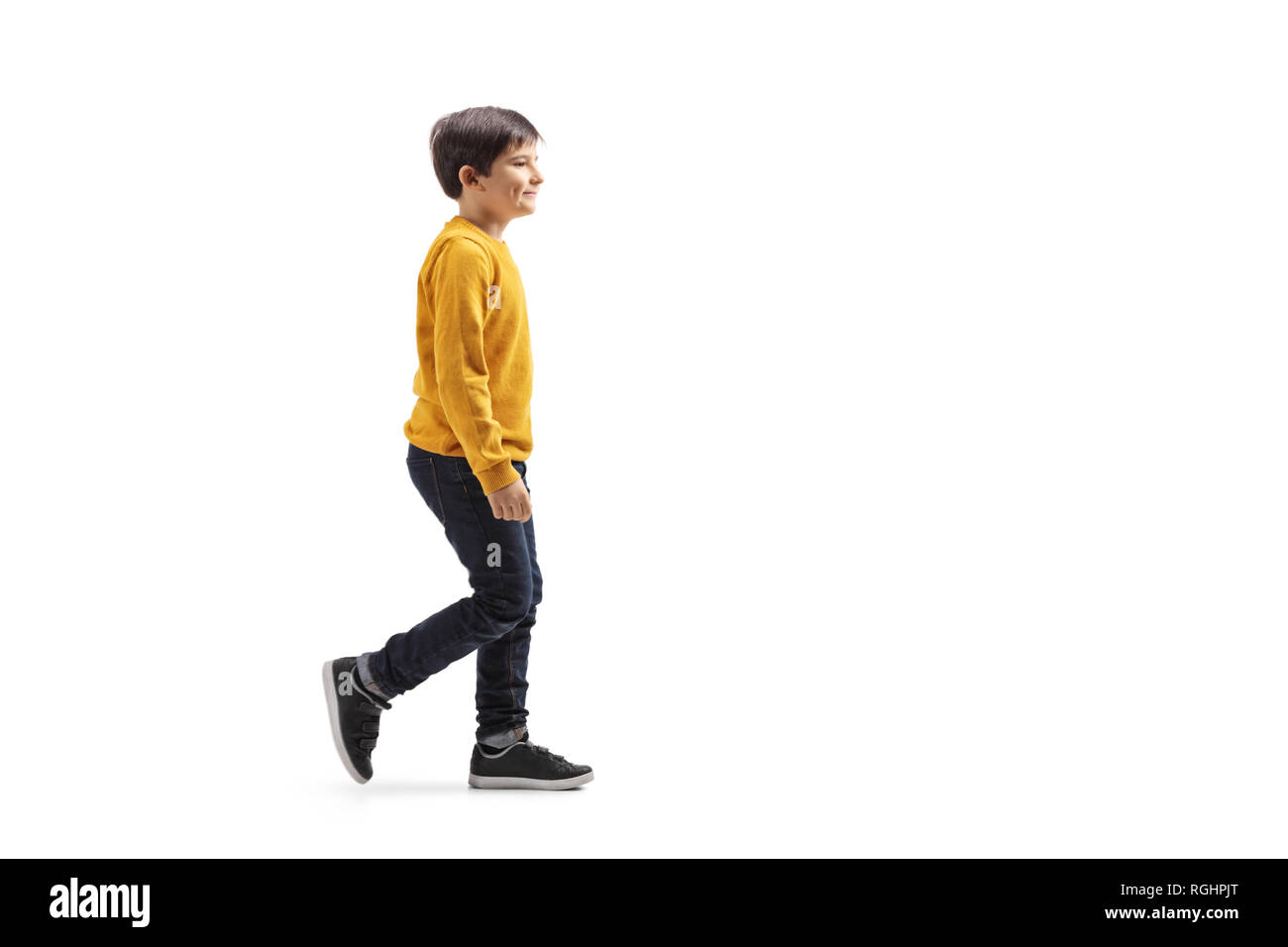 Full length profile shot of a boy walking and smiling isolated on white background Stock Photo