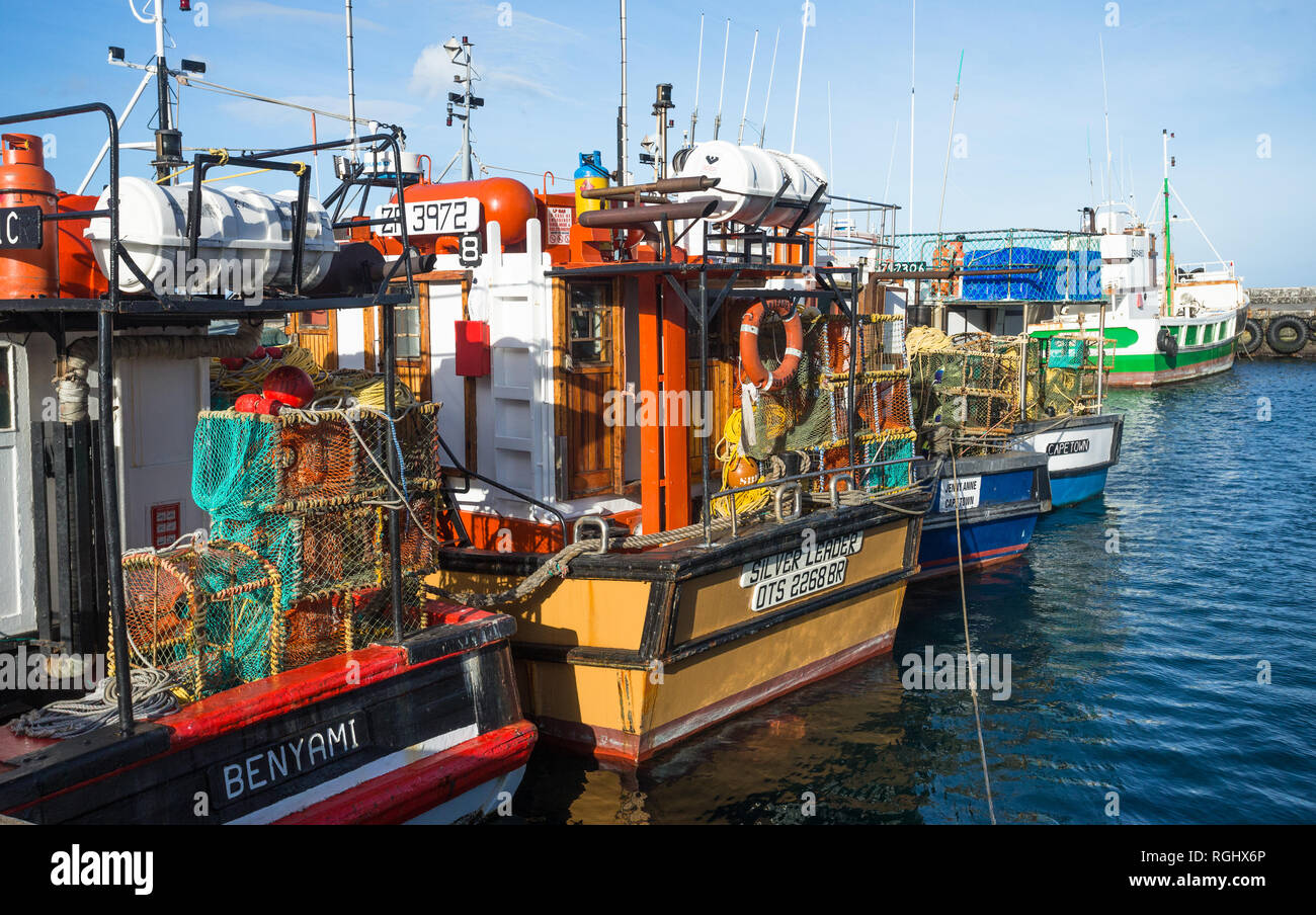 lobster or crayfish pots on industrial fishing boats lined up in a row and moored or tied up together in Kalk Bay harbour, Cape Town, South Africa Stock Photo