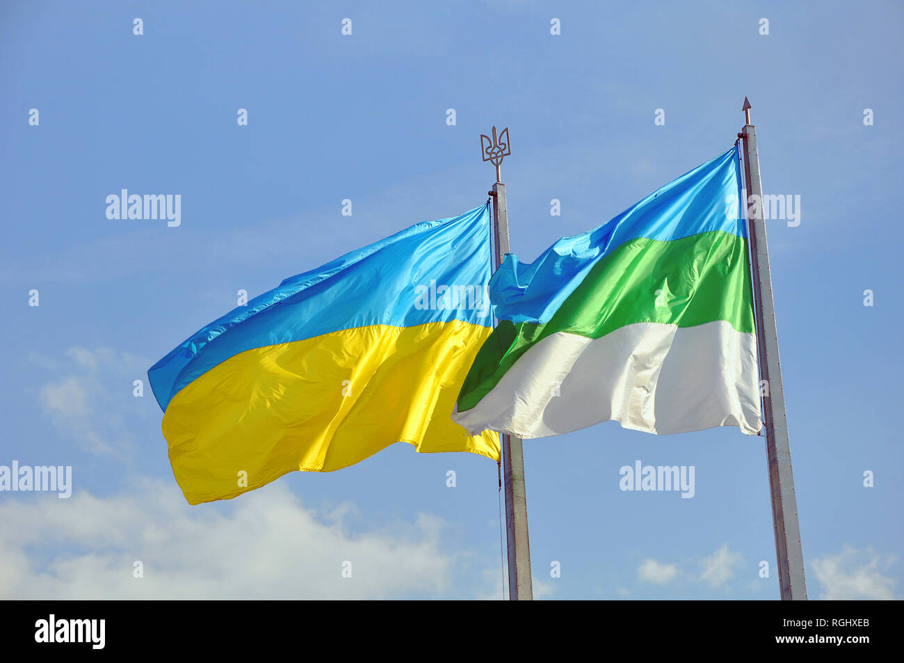 Two Ukrainian flags waving on the wind - Ukraine national blue & yellow and tricolor of city Rivne Stock Photo