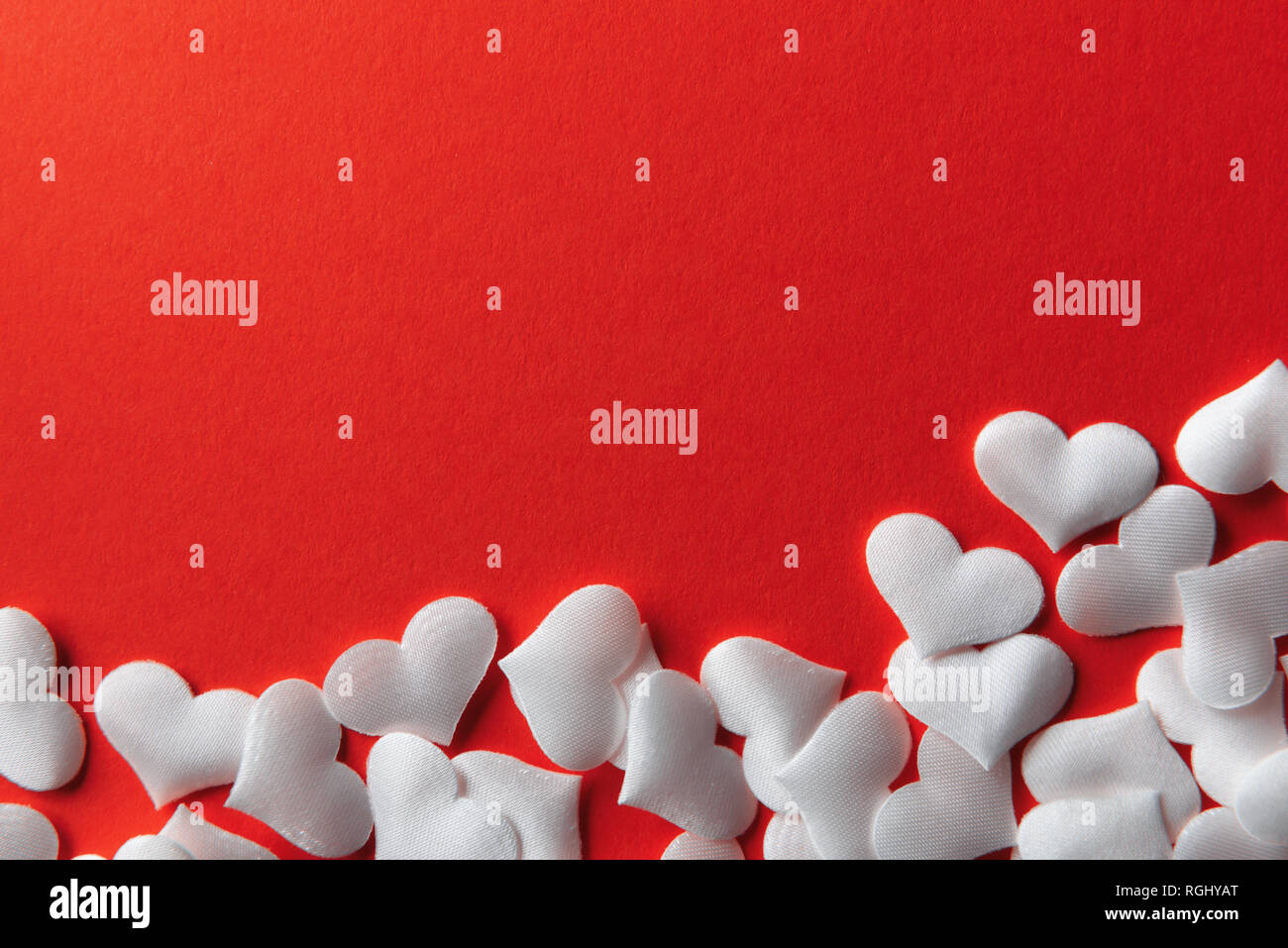 White textile hearts on red background closeup. Valentines day card, creative texture and love concept Stock Photo