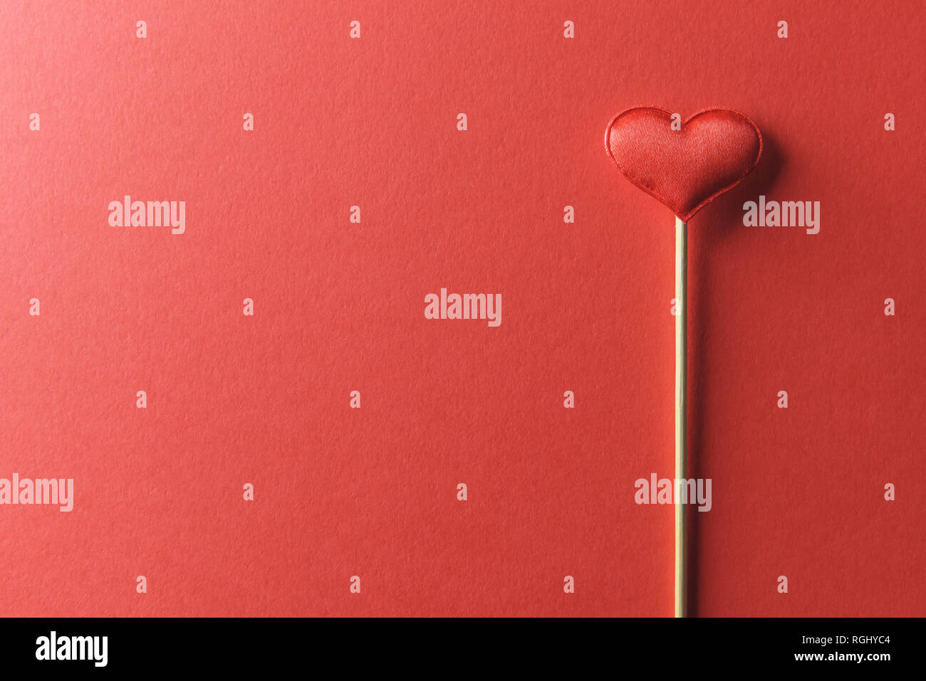 Red textile heart on wooden stick closeup. Valentines day background, creative texture and love concept Stock Photo