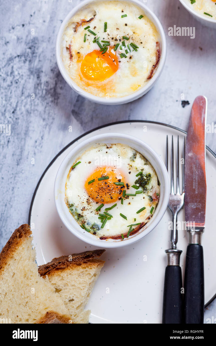 Oefs en cocotte (Individual baked eggs) with spinach, feta, bacon, eggs, and slices of bread Stock Photo