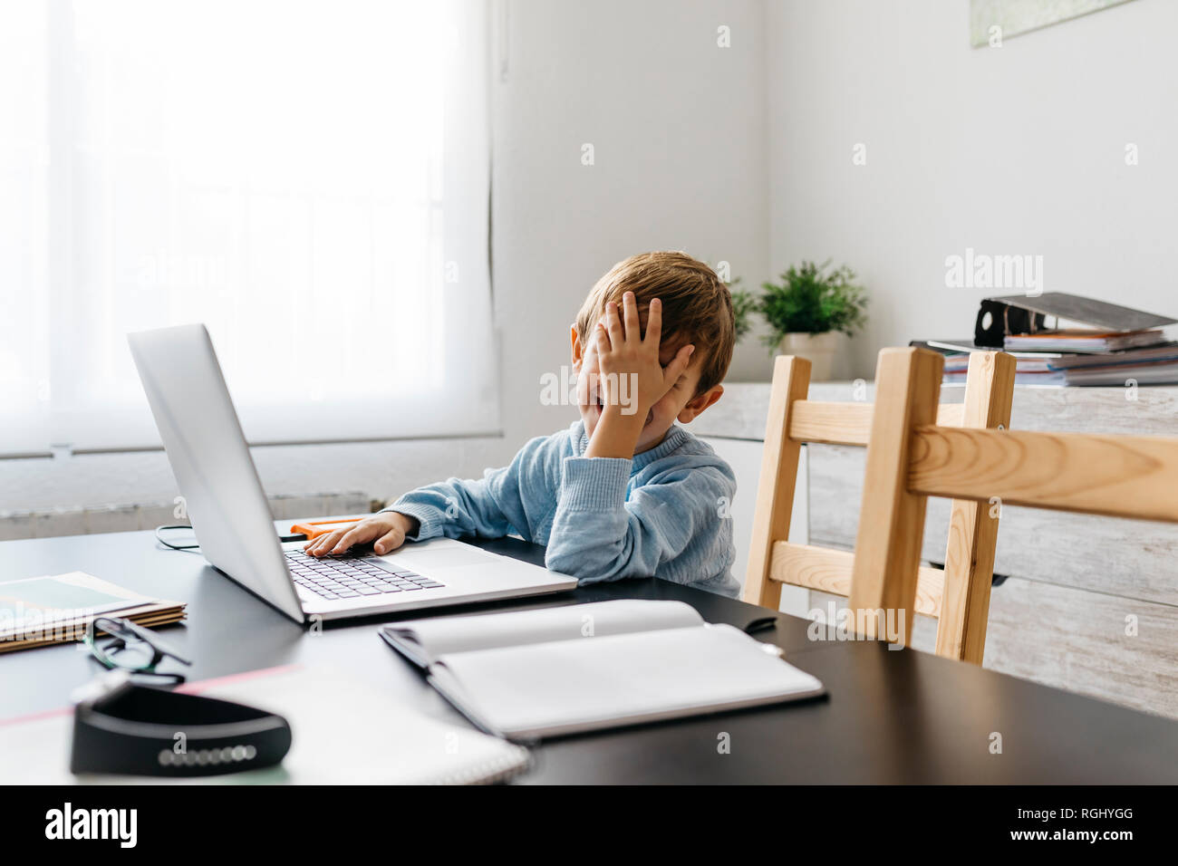 Little boy sitting in his father's office, using laptop Stock Photo