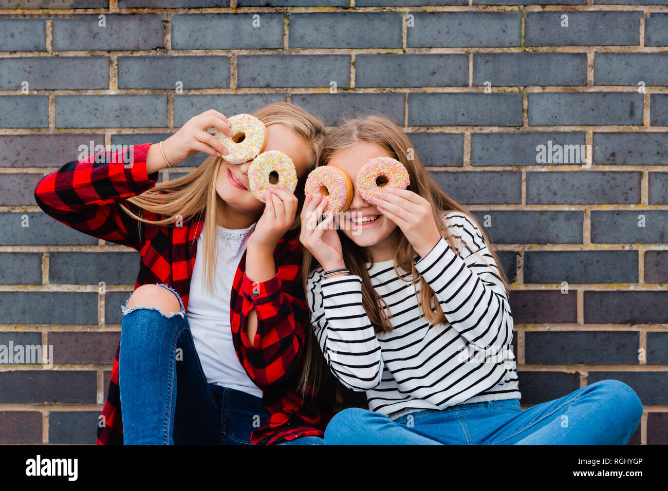 Two girls having fun with doughnuts Stock Photo