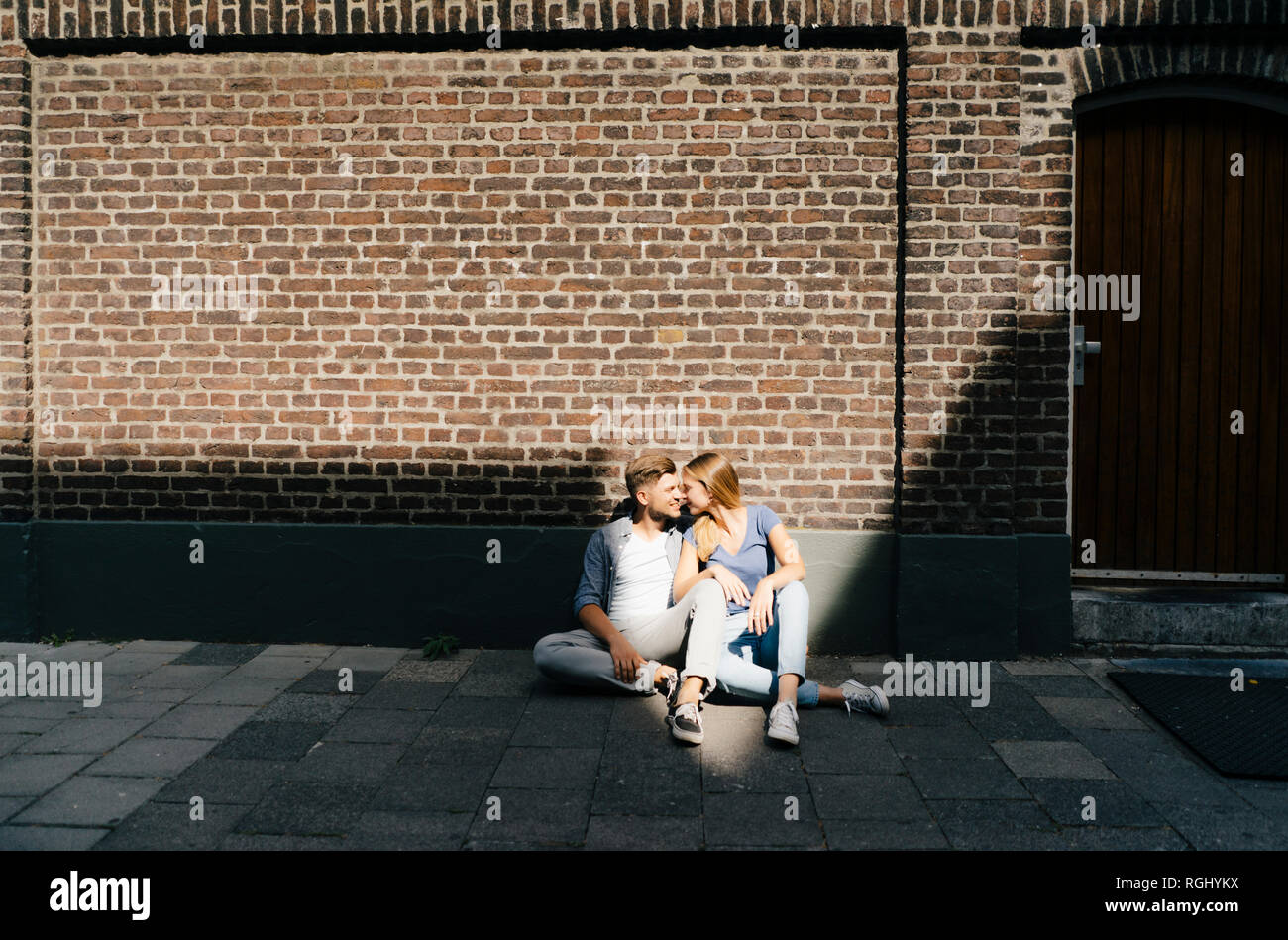 Netherlands, Maastricht, young couple having a break in the city sitting on sidewalk Stock Photo