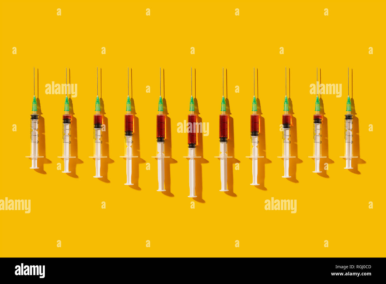 Multiple syringes organized in a pattern over yellow background Stock Photo