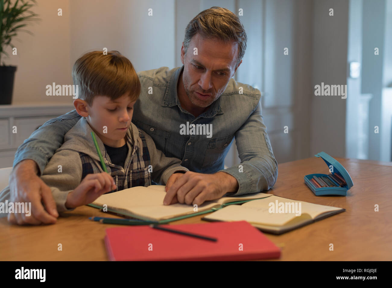 Front view of loving father helping his son with his homework at home Stock Photo